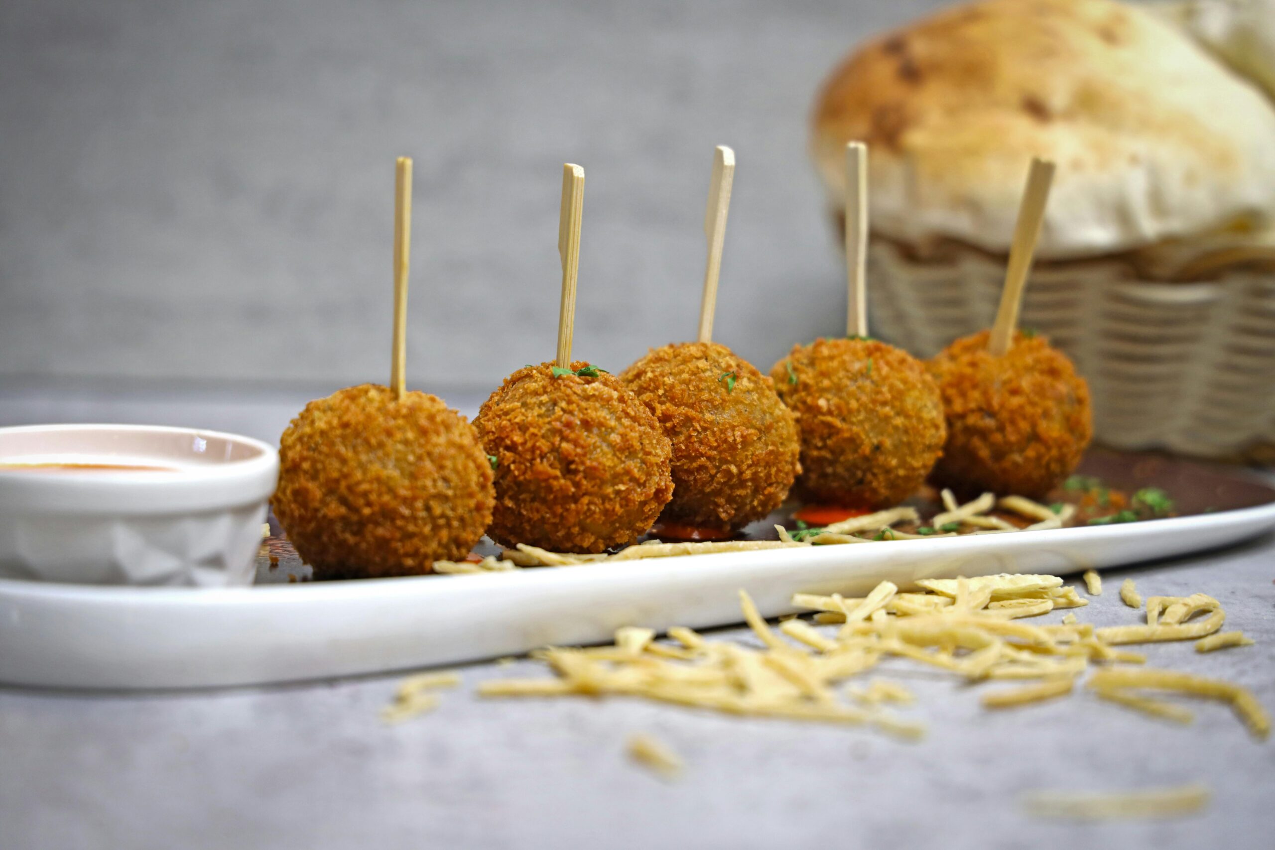 Tasty golden appetizer balls served with a spicy sauce, perfect for gatherings.
