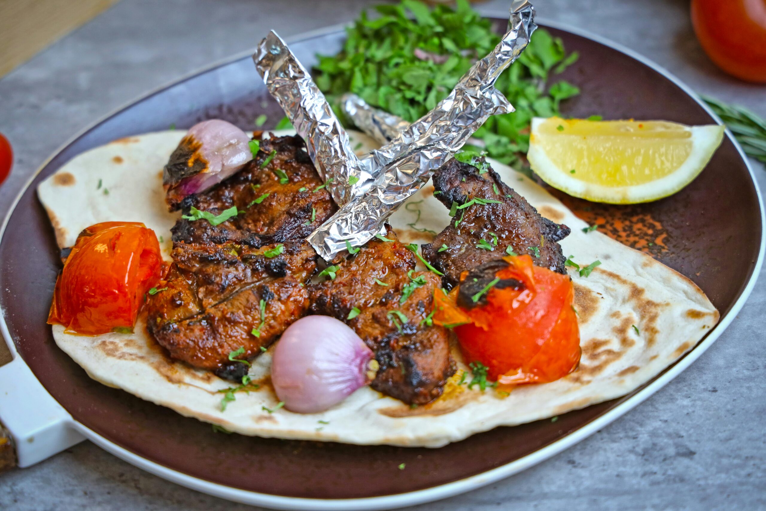 Delicious grilled kebabs served with veggies and lemon on flatbread, perfect for lunch or dinner.