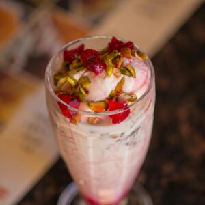 A tempting glass of falooda topped with pistachios and rose syrup, captured elegantly in Dubai.
