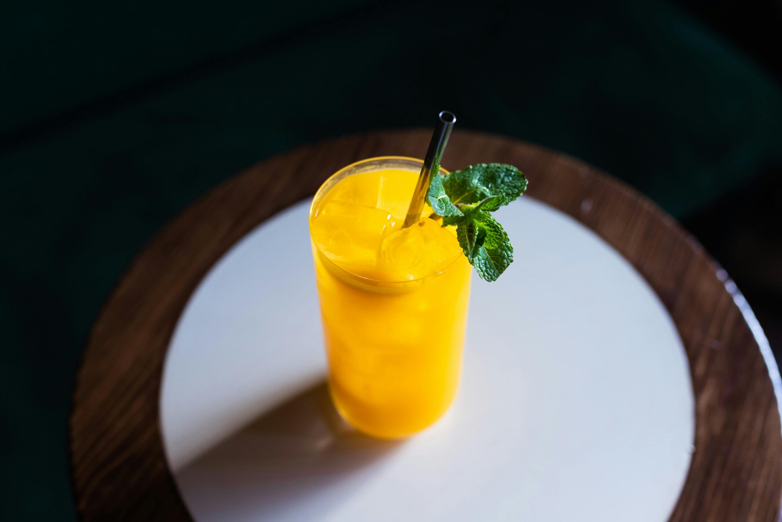 A top view of a refreshing mango juice with mint on a wooden table.